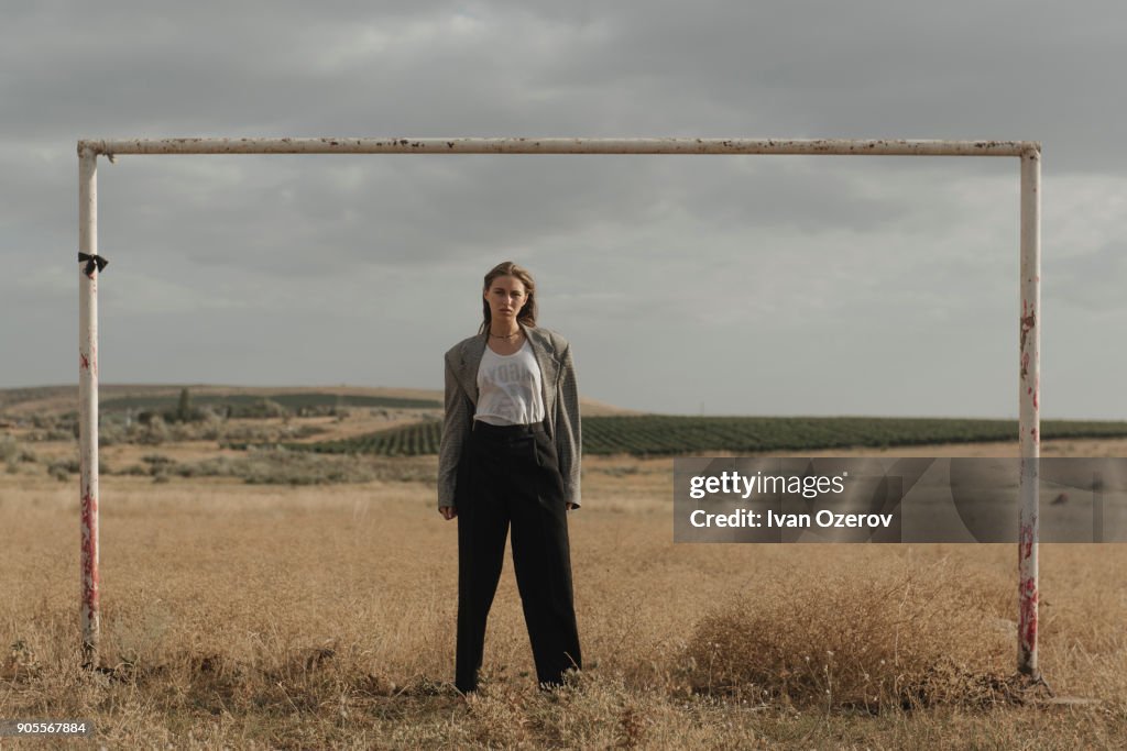 Serious location woman standing in worn soccer goal