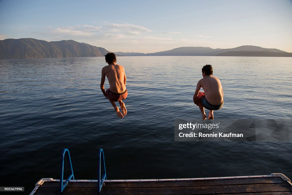 Boys jumping into lake from dock