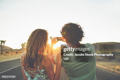 Hispanic couple photographing sunset in street Hispanic couple photographing sunset in street
