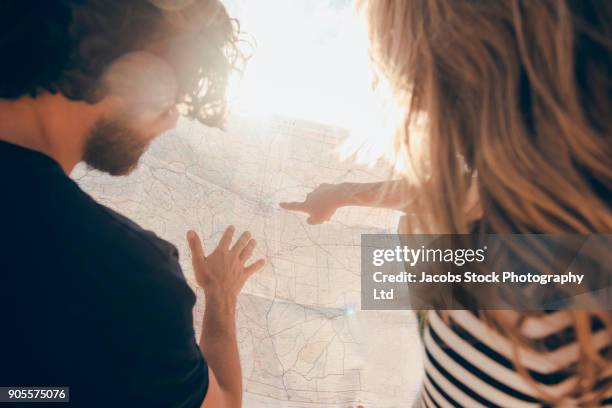 hispanic couple reading map in desert - touch map stock-fotos und bilder