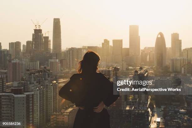 vista posterior de la mujer en ciudad del sol - mano sobre la cadera fotografías e imágenes de stock