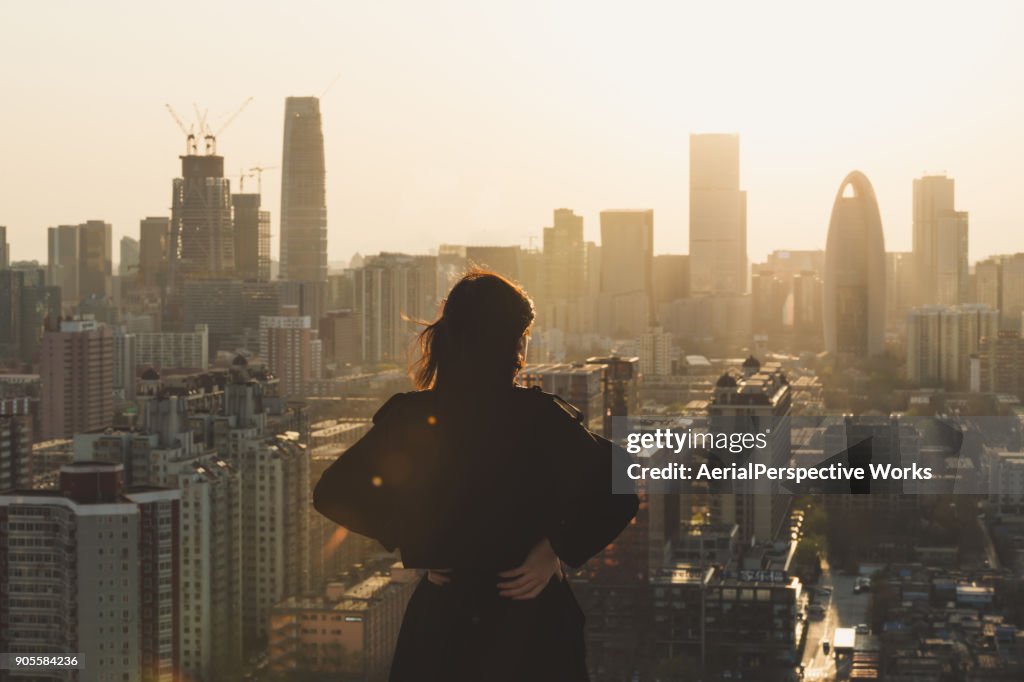 Rear view of Woman looking at city in Sunlight