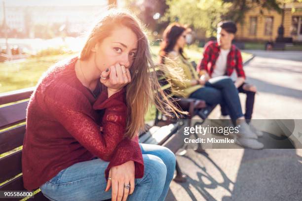 young woman looking at camera and sitting alone on the park bench. - covet stock pictures, royalty-free photos & images