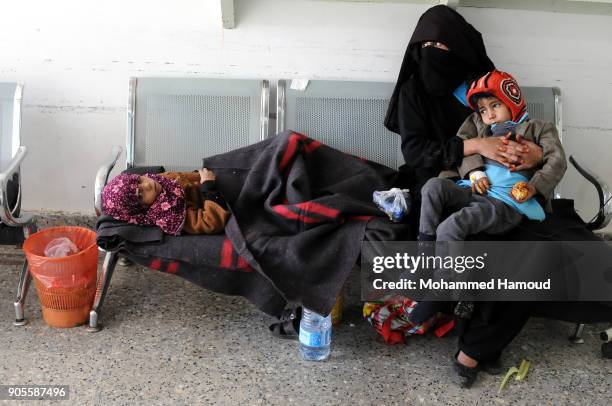 Yemeni mother sits by her malnourished children on an chair at a corridor while they receives medical treatment at a malnutrition center amid...