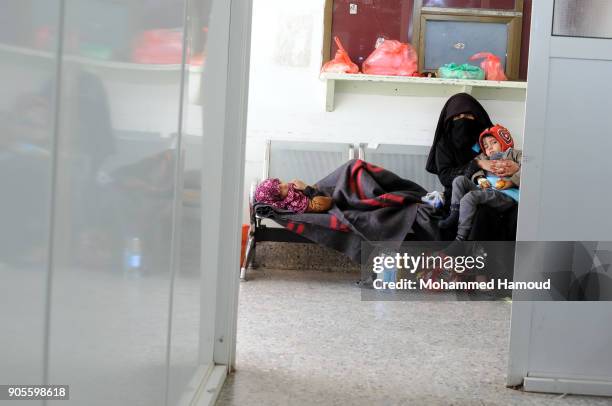 Yemeni mother sits with her malnourished children on an chair at a corridor while they receives medical treatment at a malnutrition center amid...