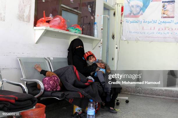 Yemeni mother sits with her malnourished children on an chair at a corridor while they receives medical treatment at a malnutrition center amid...