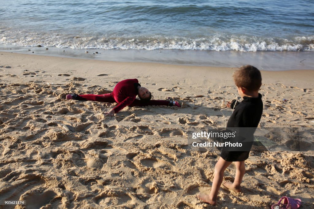 A Palestinian girl 10 y.o. demonstrates acrobatics skills on a beach in Gaza