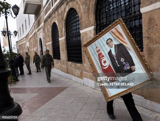 Tunisian employee of the Prime ministry removes a portrait of former Tunisian president Ben Ali to on January 17, 2011. The Moroccan press welcomed...