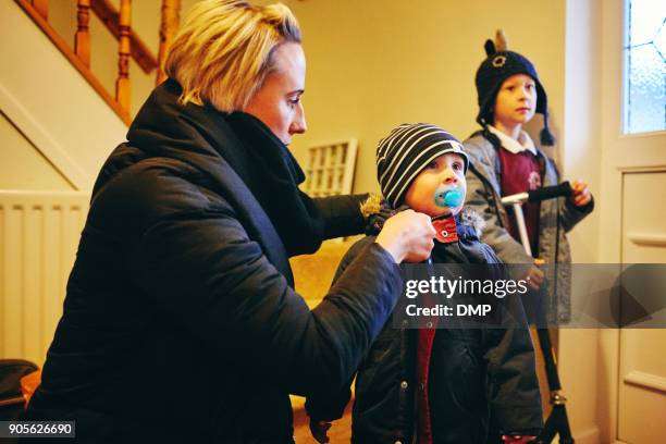 mum helping kids get their coats on - busy mother stock pictures, royalty-free photos & images