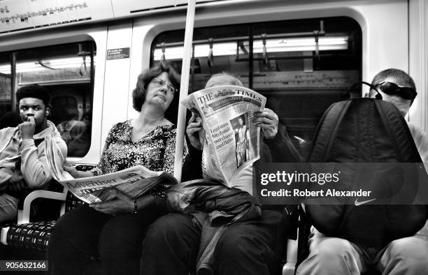 Couple read newspapers while riding in an underground train in London, England.