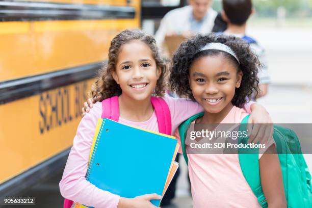 two schoolgirls smile for camera on first day - public service announcement stock pictures, royalty-free photos & images