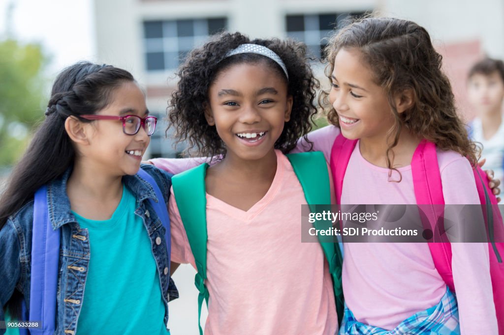 Three schoolgirls embrace on first day of school