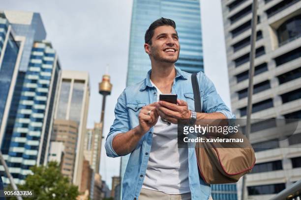 young man looking for a meeting point in the city - person looking at phone while smiling australia stock pictures, royalty-free photos & images