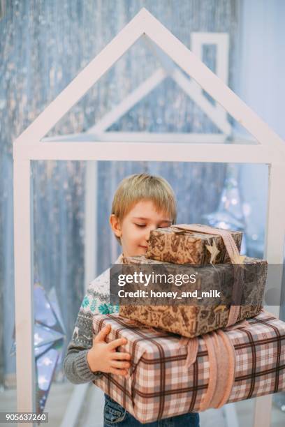 boy holding a stack of christmas gifts - honey boy fotografías e imágenes de stock