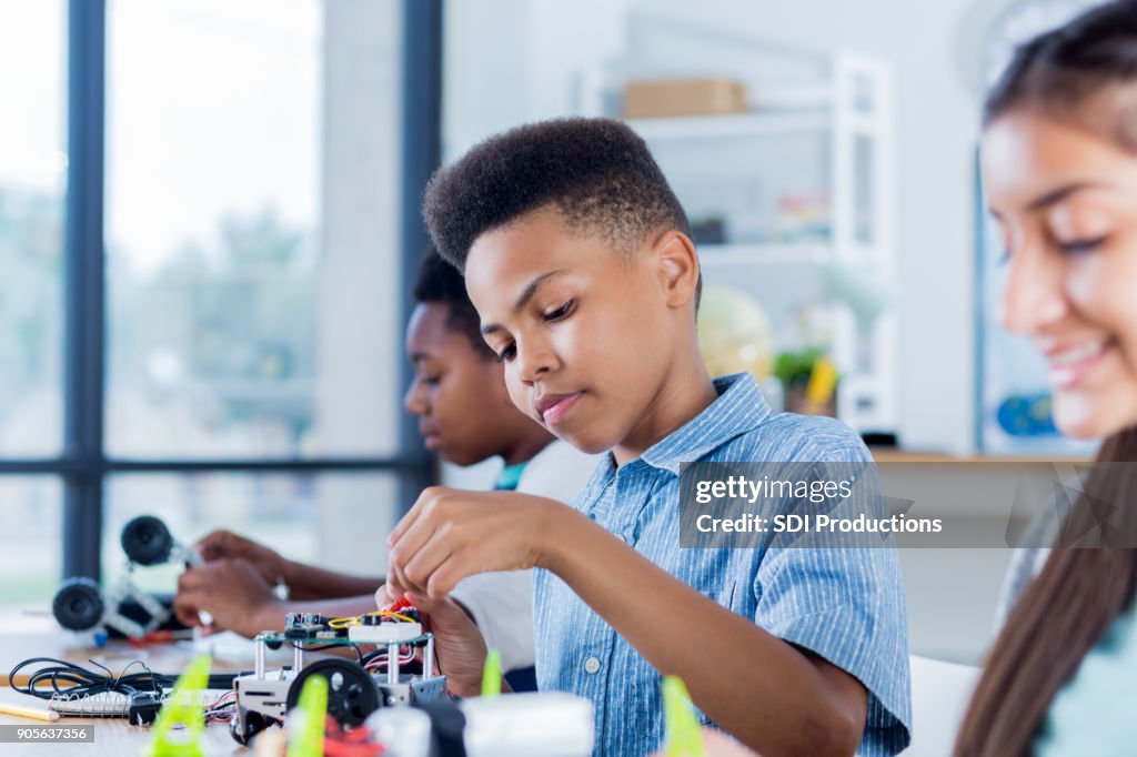 Preteen boy works on robotics project at school