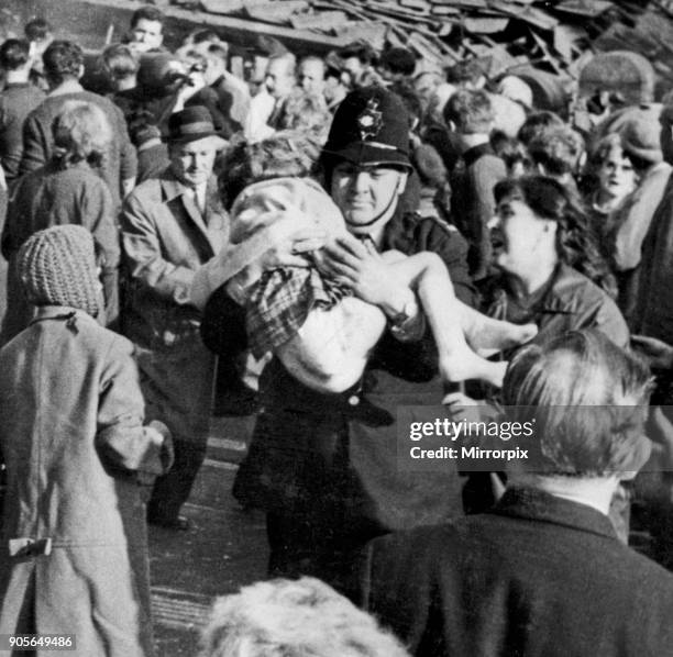 Policeman Victor Jones carries a little girl from the wrecked school as woman anxiously looks to see if she can recognise her - Picture taken by...
