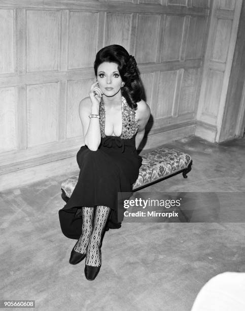 Joan Collins in the Park Street flat she has rented, wearing her favourite evening dress of black crepe with a halter bodice with brilliantly...