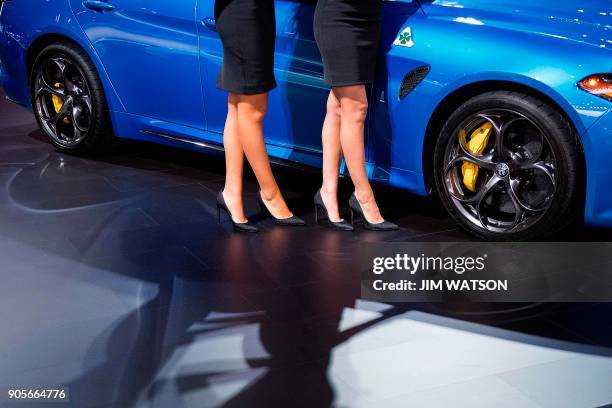 Two models stand near the Alfa Romeo Giulia during the 2018 North American International Auto Show in Detroit, Michigan, on January 15, 2018. / AFP...