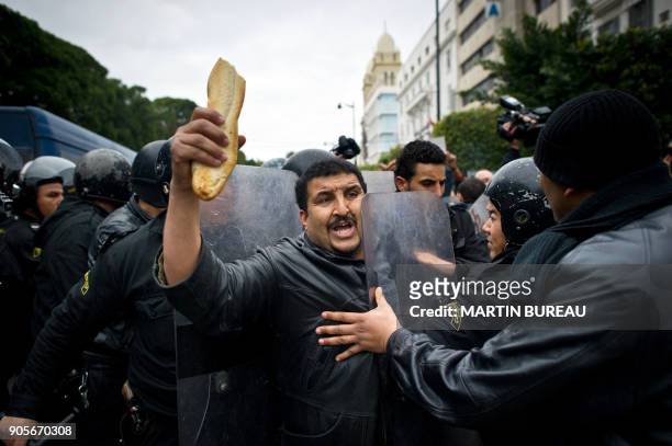 Tunisian protester holding bread is pushed by riot policemen during a demonstration in Tunis on January 18, 2011. Riot police fired tear gas and...