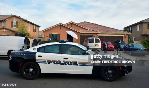 Police car parks in front of 160 Muir Woods Road from where authorities rescued 13 malnourished children held captive by their parents in Perris,...