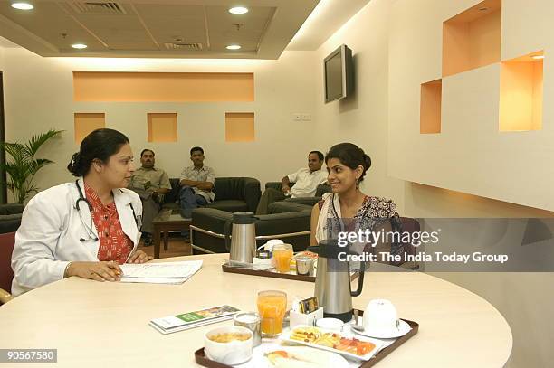 Doctor speaks to a patient as others wait in the preventive care lounge at Fortis Hospital.