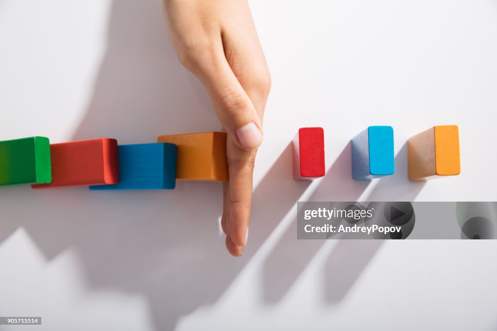 Homme d’affaires main s’arrêtant les blocs colorés de tomber