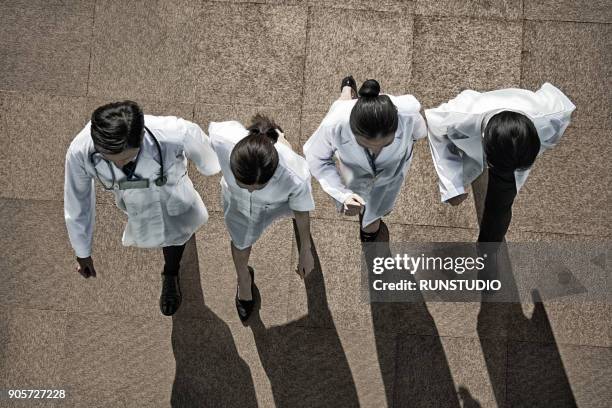 group of doctors walking outdoors - four people walking stock pictures, royalty-free photos & images
