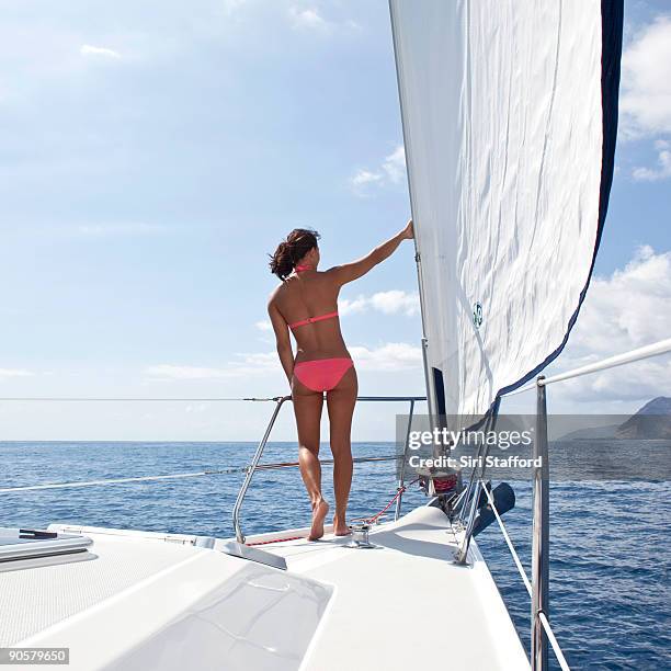 young woman standing on bow of sailboat - siri stafford fotografías e imágenes de stock