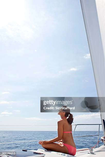 young woman meditating on bow of sailboat - siri stafford fotografías e imágenes de stock