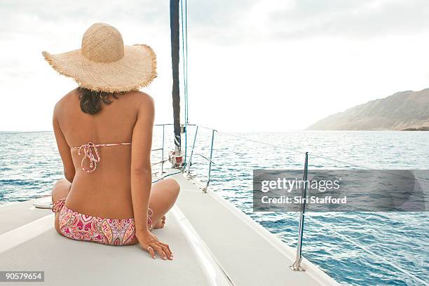 woman sitting on bow of sailboat wearing straw hat - siri stafford fotografías e imágenes de stock