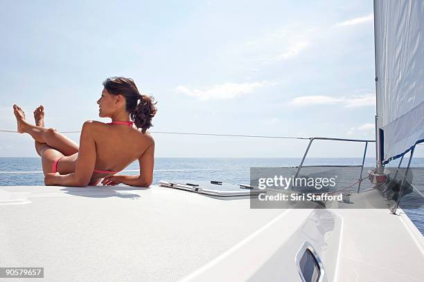 young woman relaxing on bow of sailboat - siri stafford fotografías e imágenes de stock