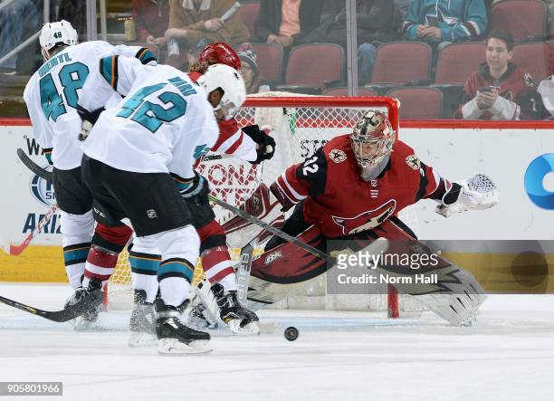 Goalie Antti Raanta of the Arizona Coyotes looks to cover the puck after making a save on the shot by Tomas Hertl of the San Jose Sharks as Joel Ward...