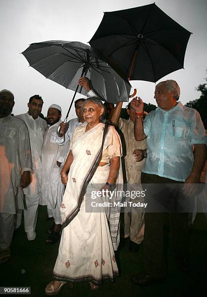 Delhi Chief Minister Shiela Dixit protects herself from the rain at an Iftar party at her residence in New Delhi on Wednesday, September 9, 2009.