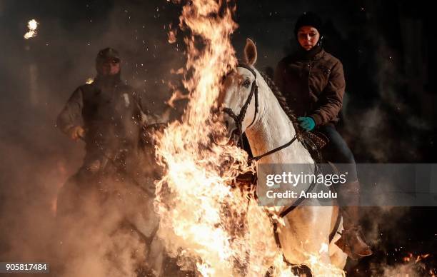 Woman rides her horse through fire to purify and protect her horse during the Las Luminarias festival at the San Bartolome de Pinares village in...