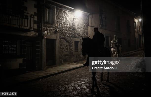 People are seen with their horse ahead of jumping through fire to purify and protect their horse during the Las Luminarias festival at the San...