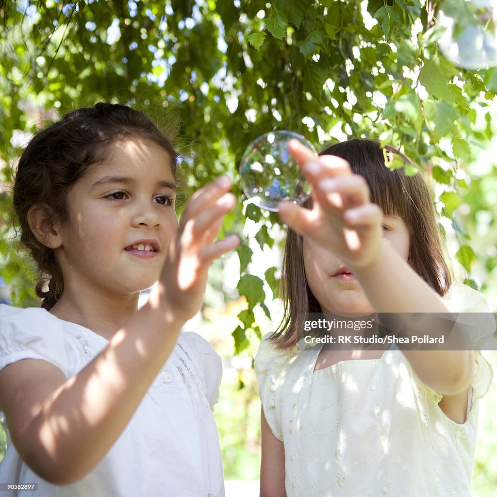 Two young girls playing with bubbles.