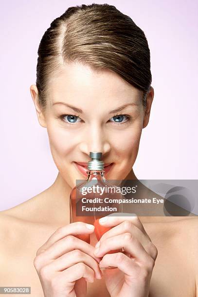 woman holding glass pump bottle up to her nose - pump schoen stock-fotos und bilder