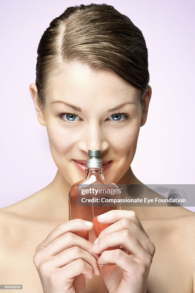 Woman holding glass pump bottle up to her nose