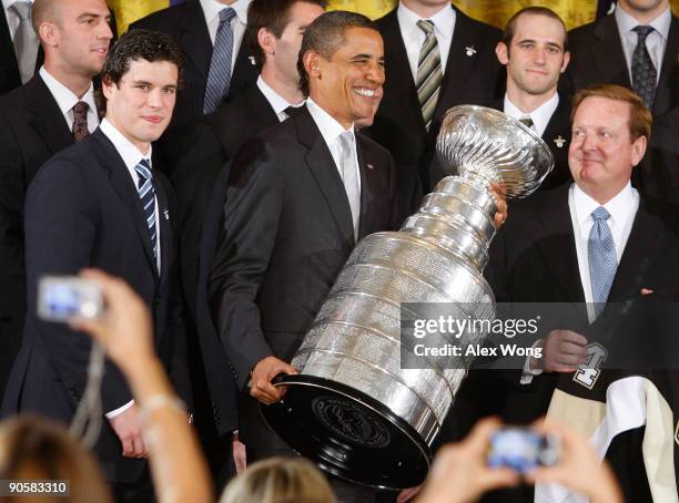 President Barack Obama holds the Stanley Cup as he poses for photographs with members of the Pittsburgh Penguins, including captain Sidney Crosby and...