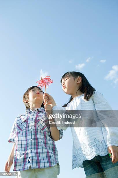 boy and girl (6-7) blowing pinwheel - 紙風車 ストックフォトと画像