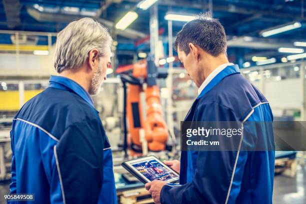 dois engenheiros examinando o braço robótico na fábrica - manufatura auxiliada por computador - fotografias e filmes do acervo