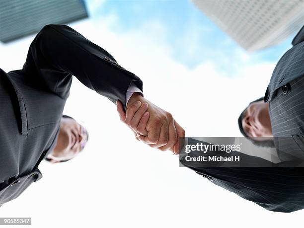 two businessmen who shake hands - low angle view of two businessmen standing face to face outdoors stock pictures, royalty-free photos & images