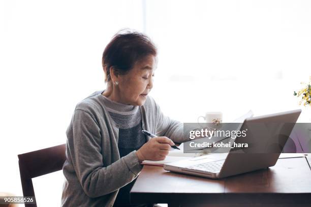 senior woman writting a document and working at home - escritura japonesa imagens e fotografias de stock