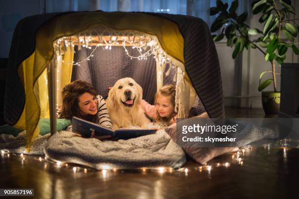 gelukkig moeder en dochter ontspannen met een hond in een tent en lezen van een boek. - entertainment tent stockfoto's en -beelden