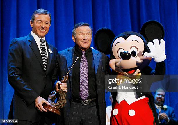 In this handout image provided by Disney, actor Robin Williams is recognized by Bob Iger, CEO of Walt Disney Co.,and Mickey Mouse for Williams' work...
