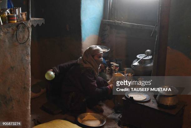 Kashmiri woman makes bread inside her home on the outskirts of Srinagar on January 17, 2018. / AFP PHOTO / TAUSEEF MUSTAFA