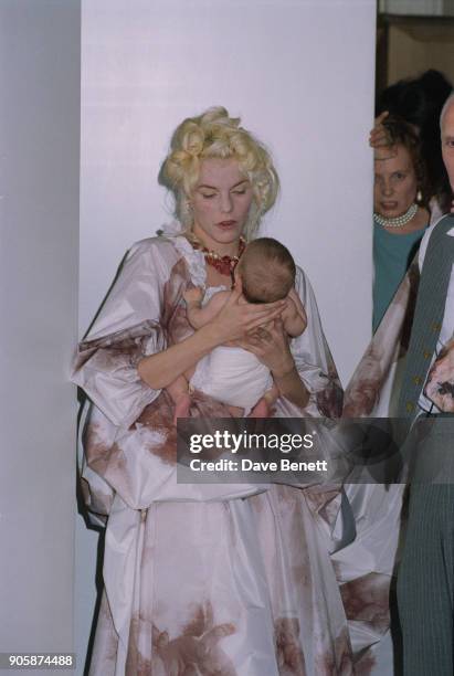 British fashion model Sarah Stockbridge walks on the catwalk holding a baby at the Vivienne Westwood Pret-a-porter Spring/Summer 1991 fashion show in...
