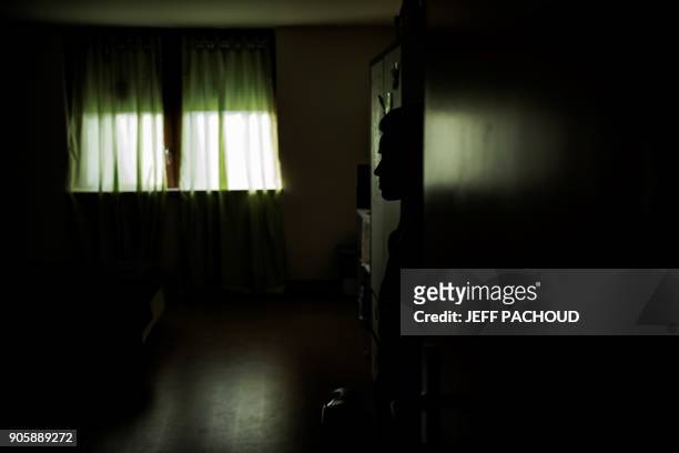 Disabled woman stands in a hallway in front of her bedroom in a 'care home' run by Chahad Khadiri on January 10, 2018 in Saint-Igny-de-Roche. Three...