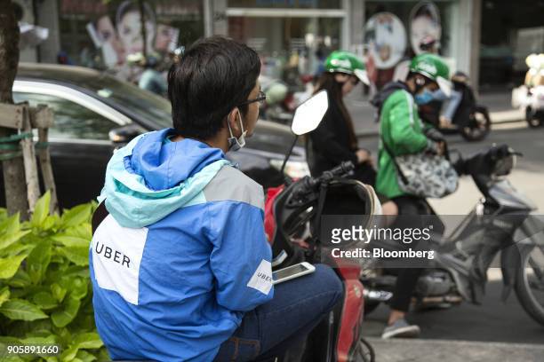 An Uber Technologies Inc. Rider sits on his motorcycle in Ho Chi Minh City, Vietnam, on Thursday, Jan. 11, 2018. A global trade recovery and Vietnams...