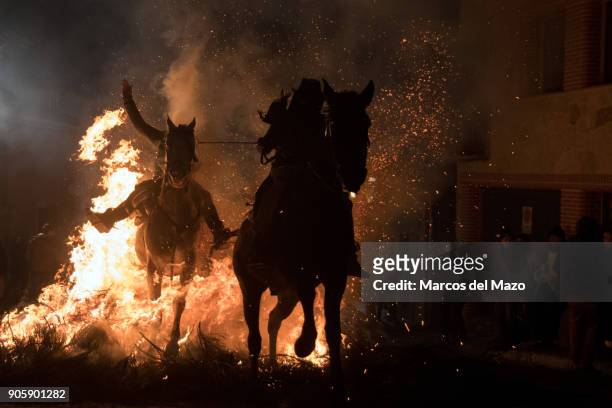 Two men ride horses through a bonfire during the traditional ritual in honor of Saint Anthony the Abbot, patron saint of domestic animals. This...